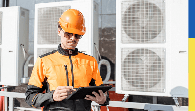 Engineer holding tablet in front of heat pumps
